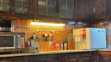 A kitchen with wooden cabinets, a microwave, a refrigerator, and a spice rack.