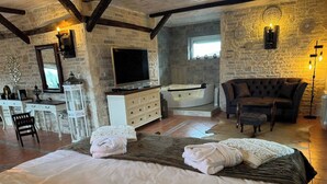 Ein gemütliches Zimmer mit einem großen Bett, einem Fernseher, einem Kamin und einer komfortablen Sitzecke.