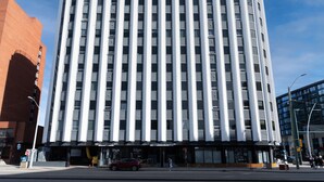 A tall, modern building with a grid of windows and a flat roof. - Chic 2-bedroom Urban Loft Condo Near Rogers Place Ice District Downtown Edmonton (Edmonton)
