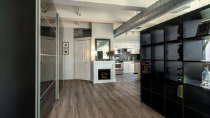 A modern kitchen with a central island, white cabinets, and a built-in fireplace. - Chic 2-bedroom Urban Loft Condo Near Rogers Place Ice District Downtown Edmonton (Edmonton)