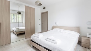 Une chambre à coucher moderne avec un grand lit, une armoire en bois et une table de chevet.
