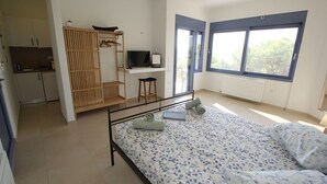 A bedroom with a bed, a desk, a TV, and a wardrobe. - Schinos by Frangki (Aegina)