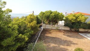 A fenced yard with trees and a building with a red roof. - Schinos by Frangki (Aegina)
