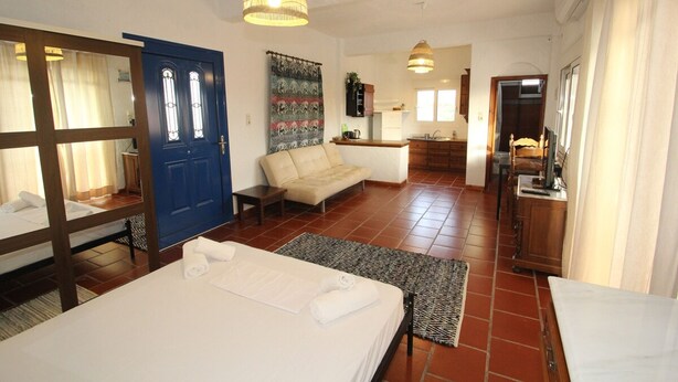 Una habitación de hotel con cama, sofá, zona de comedor y cocina.