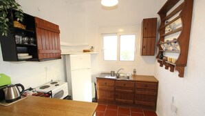 Una cocina compacta con armarios de madera, un refrigerador blanco y un ventanal que proporciona luz natural.
