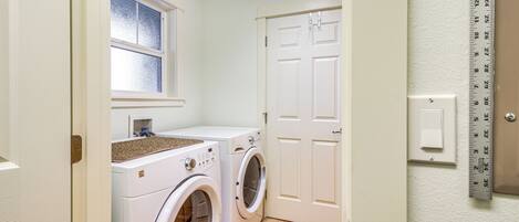 A laundry room with two washing machines, a window, and a door.