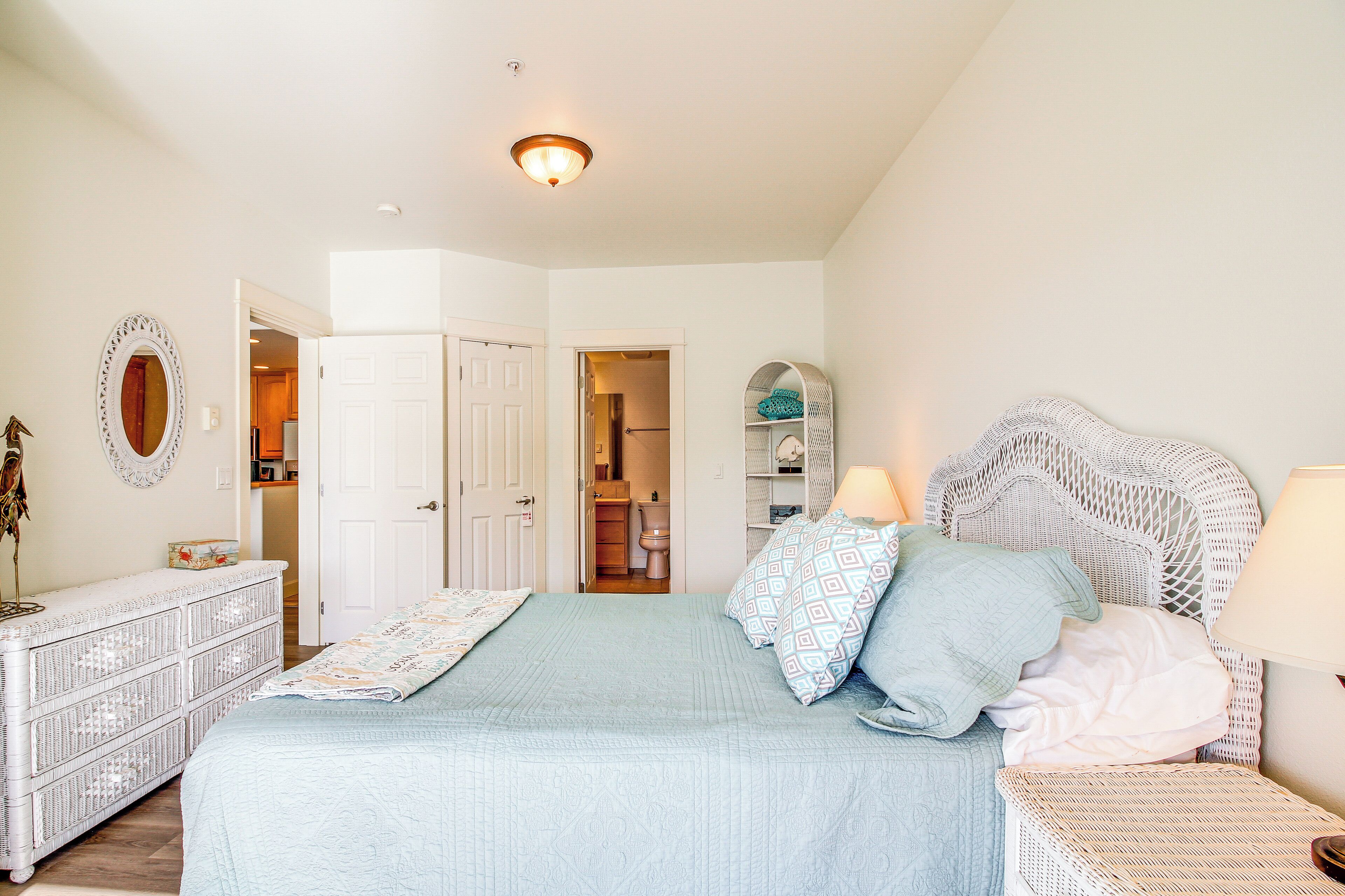 A bedroom with a bed, dresser, and a door leading to a bathroom.