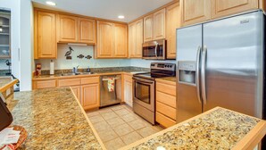 A kitchen with wooden cabinets, stainless steel appliances, granite countertops, and a tiled floor. - Riverfront Apt in Old Town Florence! (Florence)