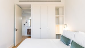 Um quarto com uma cama, um guarda-roupa e uma mesa de cabeceira com uma luminária.