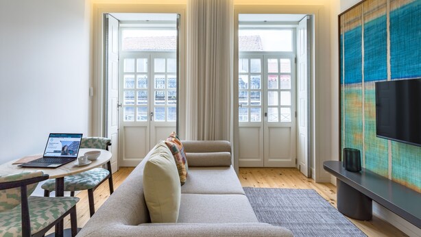 Un salon moderne avec un canapé, une table basse, un ordinateur portable et un téléviseur.