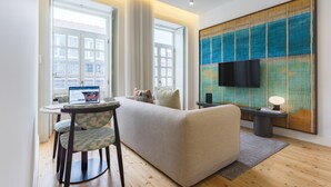 Un salon moderne avec un canapé, un coin repas comprenant une table et des chaises, un téléviseur à écran plat fixé au mur et de grandes fenêtres.