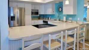 Een moderne keuken met witte kasten, roestvrijstalen apparatuur en een centraal eiland met een bar.