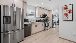 A modern kitchen with stainless steel appliances, wooden cabinets, and a large window. - 3-bedroom house on 2F in peaceful Daly City with AC, WiFi. (Daly City)