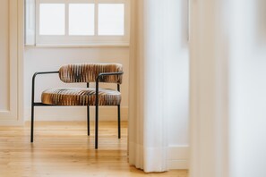 A chair with a striped cushion in a room with wooden flooring and a window with white curtains. - Feel Porto Cl Rigos Charm Flat 1 1 (Porto)