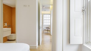 Un couloir d’hôtel avec une salle de bain à gauche, un espace repas au centre et une chambre à droite.