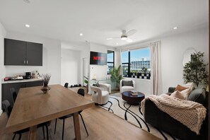 Ein modernes Wohnzimmer mit Essbereich, Küche und großem Fenster mit Blick auf die Stadt.
