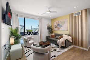 Un soggiorno moderno con divano, poltrone, tavolino e televisore a parete.