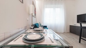 A dining area with a glass table set for two, featuring plates and cutlery. - Italianway Comfort - Serra 16 (Milano)