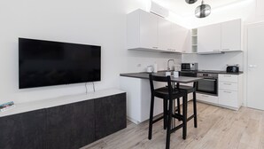 A modern kitchen with a flat-screen TV, a dining area with two chairs, and a built-in oven. - Italianway Comfort - Serra 16 (Milano)