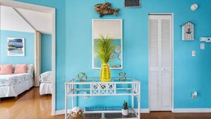 Une pièce avec un mur bleu, une console blanche ornée d’objets décoratifs, un tableau encadré et une armoire blanche.