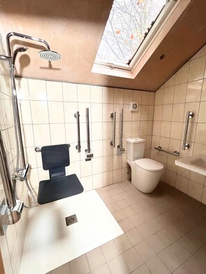 Un baño moderno con tragaluz, ducha, inodoro y lavamanos.