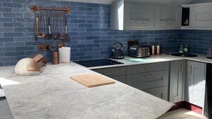 A modern kitchen with blue tiles, a skylight, and stainless steel appliances. - Luxury Lodge Palms 3 with hot tub - Accessible Access (North Connel)