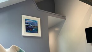A bedroom with a bed, a framed painting, and a stack of towels. - Luxury Lodge Palms 3 with hot tub - Accessible Access (North Connel)