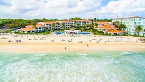 Een strandhotel met meerdere gebouwen, een zwembadgedeelte en een zandstrand.