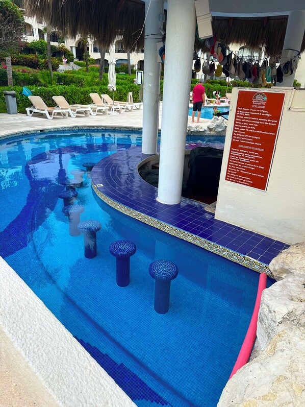 Una piscina con borde de azulejos, sillas de descanso y un cartel con normas.