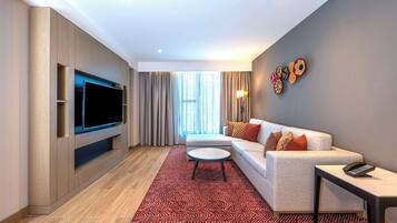 A modern living room with a flat-screen TV, a sofa, a coffee table, and a patterned rug.