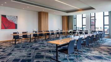 Une salle de conférence avec une longue table, des chaises et un tapis à motifs.