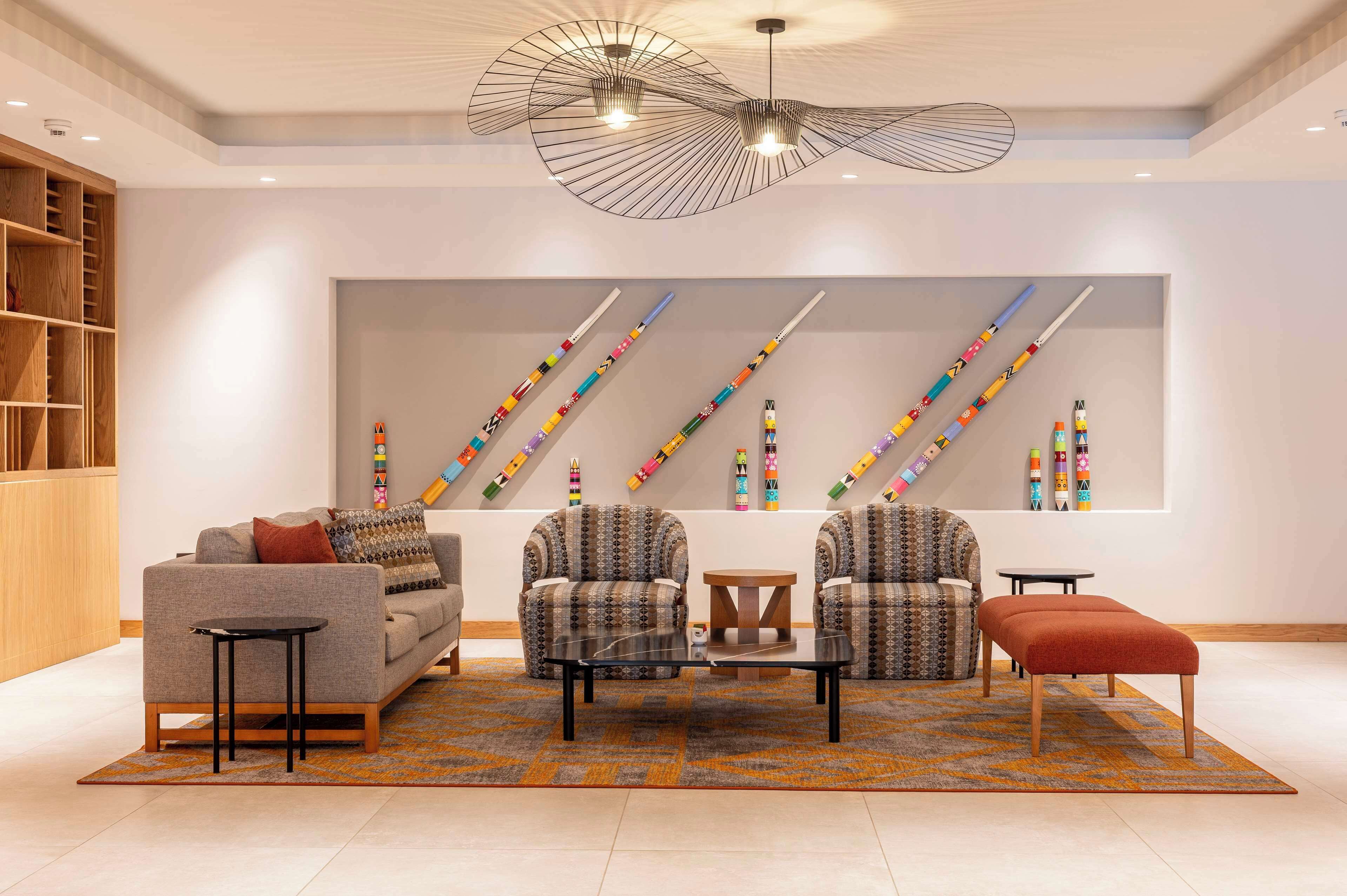A modern living room with a sofa, armchairs, a coffee table, and a patterned rug.