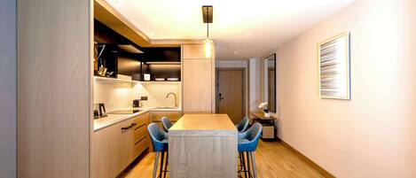 A modern kitchen with wooden cabinets, a central island, bar stools, and a pendant light.
