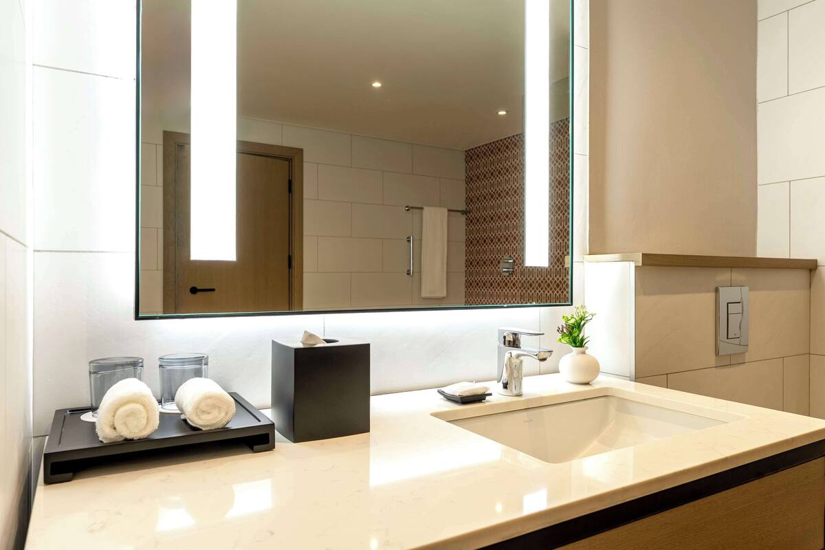 Un baño moderno con un espejo grande, un lavabo y un perchero para toallas.