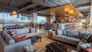 Un área de estar moderna con sofás, una mesa de billar y una zona de bar con taburetes.