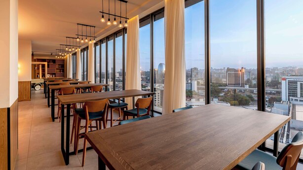 Un comedor moderno con ventanas amplias, mesas y sillas de madera.