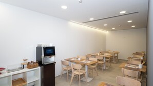 Une chambre d’hôtel équipée d’une kitchenette, d’une machine à café et d’un coin repas avec tables et chaises.