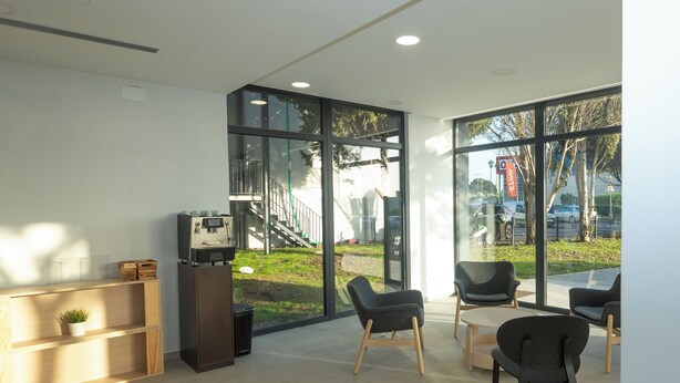 Une pièce moderne et bien éclairée, dotée de grandes fenêtres, d’un comptoir d’accueil et d’un espace salon.