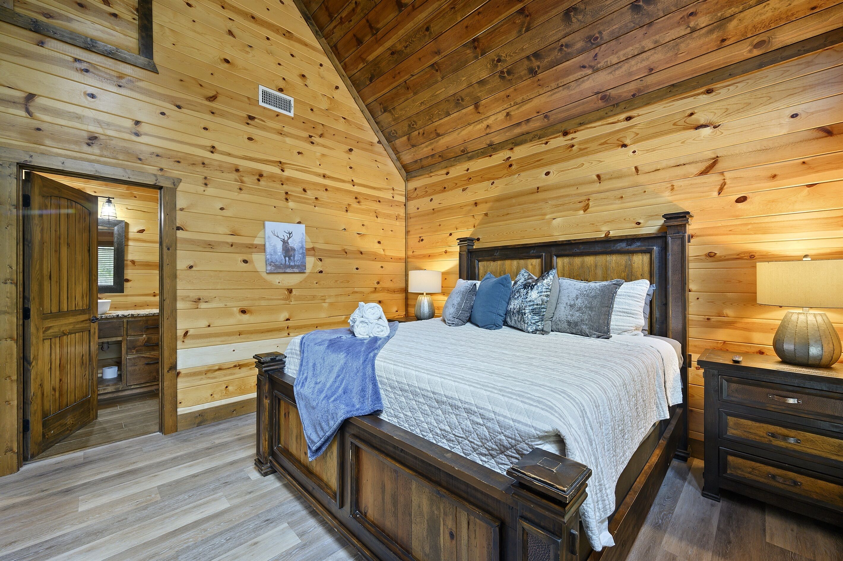Ein Schlafzimmer mit Holzwandverkleidung, einem Bett, Nachttischen und einer Tür zu einem anderen Raum.