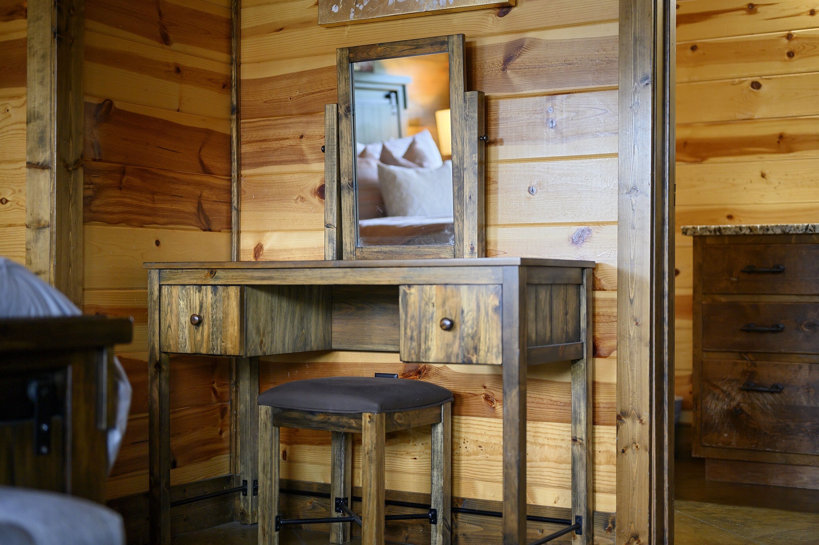 A wooden cabin interior with a wooden desk and a mirror.