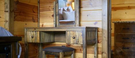 A wooden cabin interior with a wooden desk and a mirror.