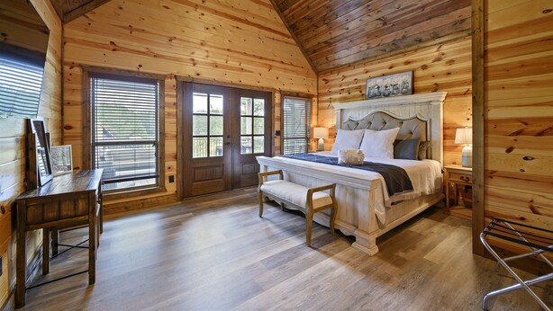A wooden cabin bedroom with a bed, bench, and desk.