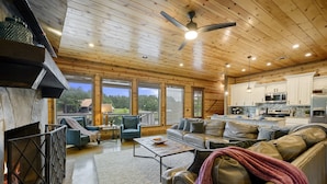 A spacious living area with a fireplace, leather sofas, and a view of the outdoors.