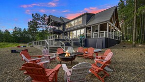 A lodge with a fire pit and red Adirondack chairs in front.