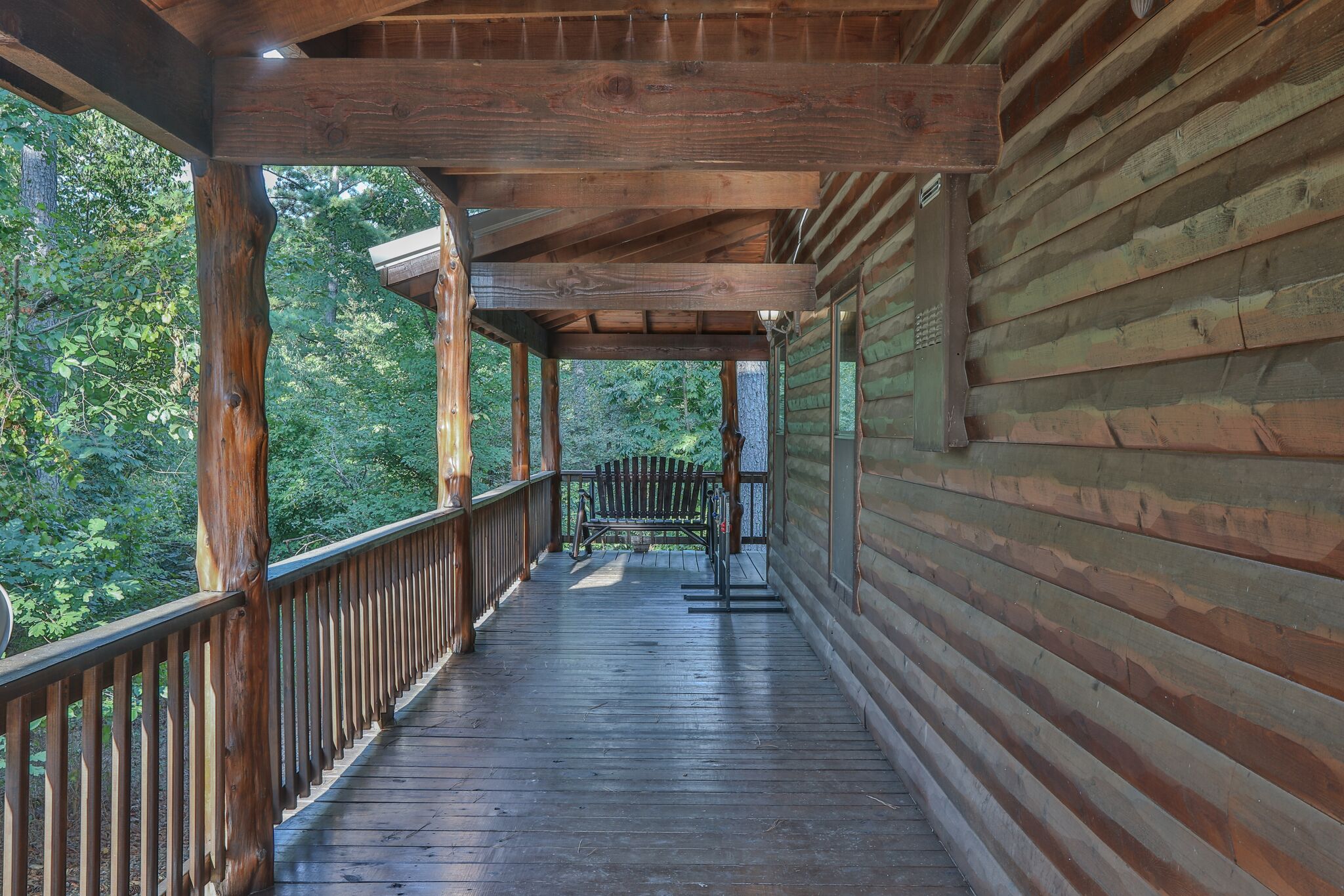 A wooden deck with a railing, surrounded by trees.