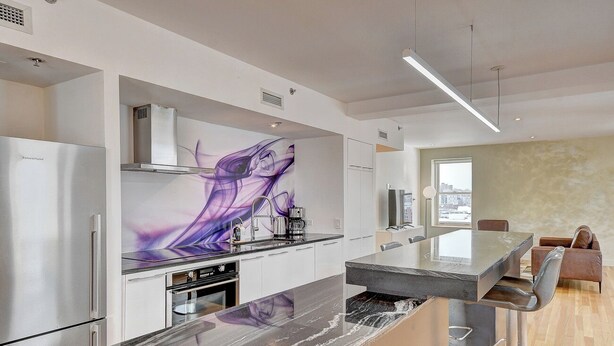 Une cuisine moderne dotée d’un plan de travail en marbre, d’appareils électroménagers en acier inoxydable et d’une grande fenêtre offrant une vue sur la ville.