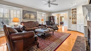 A spacious living room with leather sofas, a large rug, and a fireplace. - Spacious Historic Manor with Chef's Kitchen • Horse-Friendly (Southern Pines)