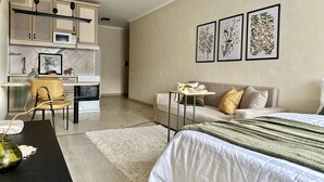 Une chambre moderne comprenant un lit, un canapé, une petite table et un coin cuisine.