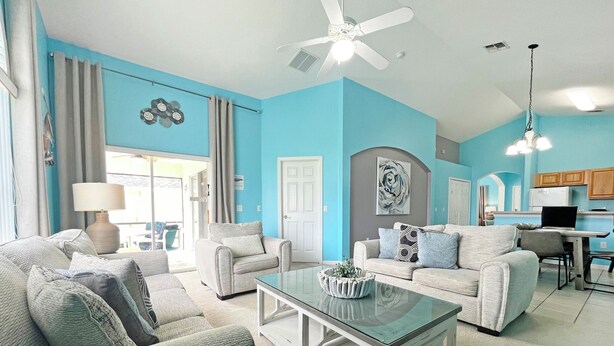 A living room with two sofas, a coffee table, and a dining area with a table and chairs. - Highgate Haven - Bright pool home with games room in gated community (Davenport)