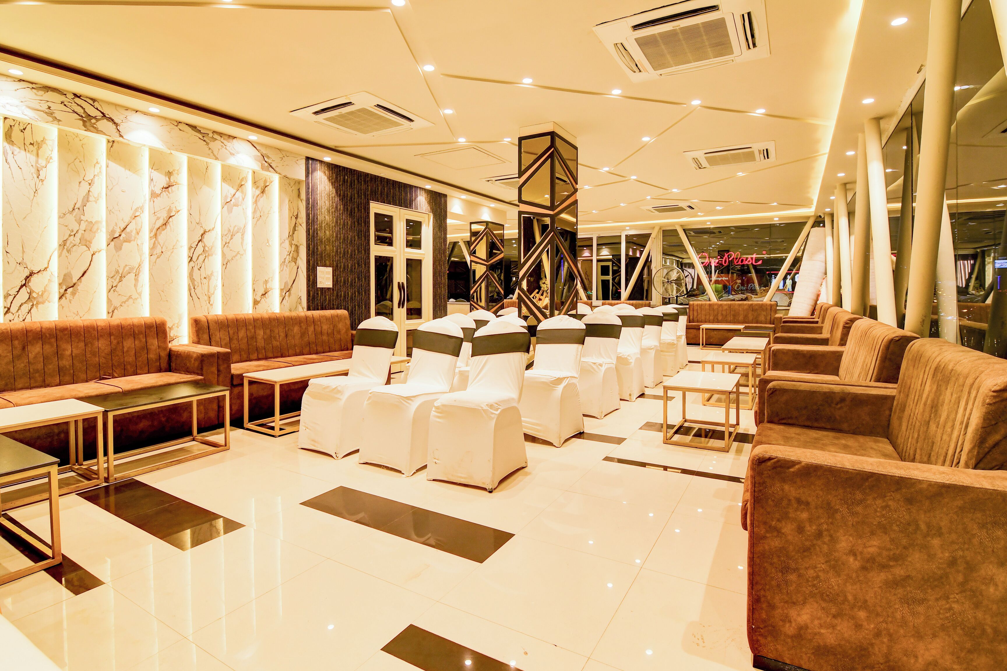 A modern hotel lobby with seating areas, a reception desk, and a decorative wall.